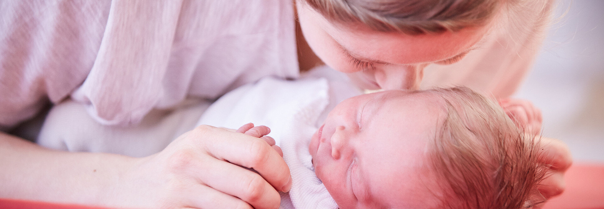 Eine Mutter schmußt ihre Nase an ihr neugeborenes Baby