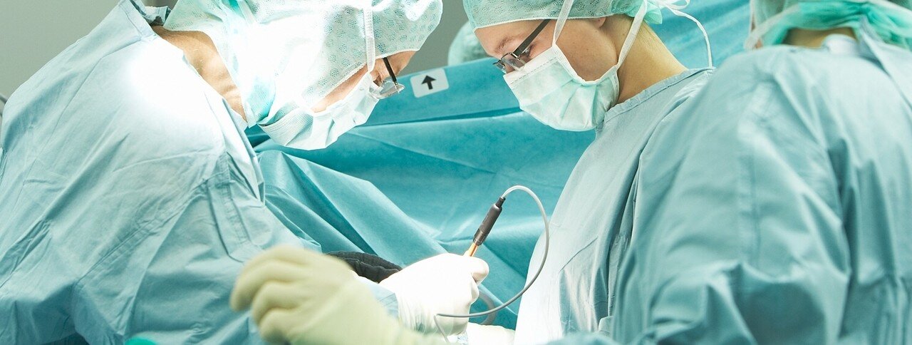 Das Bild zeigt drei konzentrierte Chirurgen im OP bei der Arbeit.